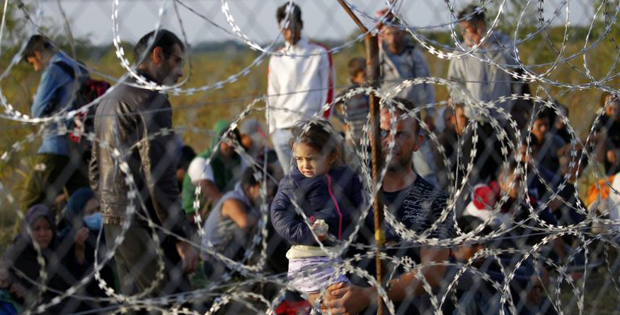 immagine di migranti dietro al filo spinato